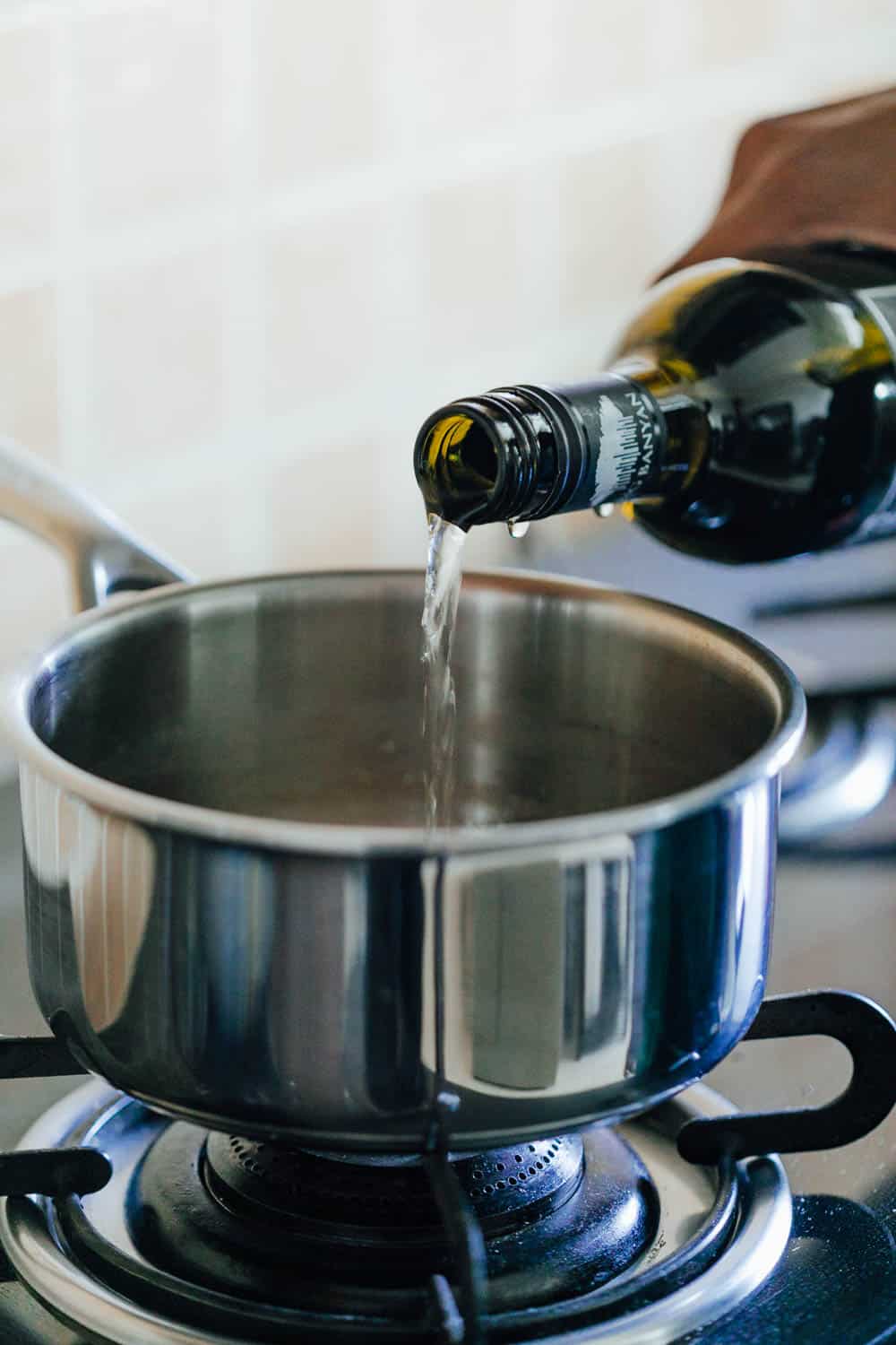 Pouring white wine to start making Easy cheese fondue recipe with white wine