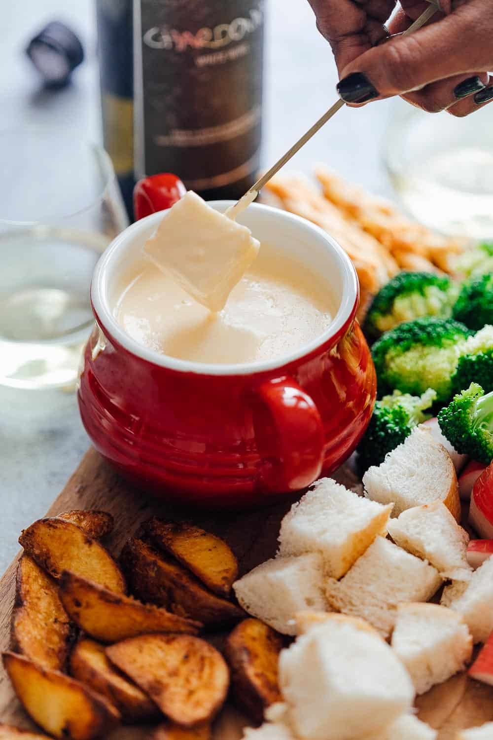Dipping bread into Easy cheese fondue recipe with white wine