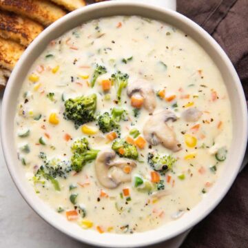 Creamy vegetable soup served in a bowl with bread on the side