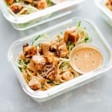 Crispy Sesame Tofu Zucchini Noodles in meal prep containers with peanut sauce.