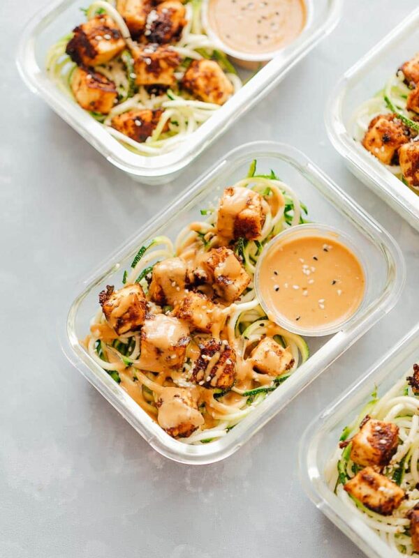 Crispy Sesame Tofu Zucchini Noodles in meal prep containers with peanut sauce.