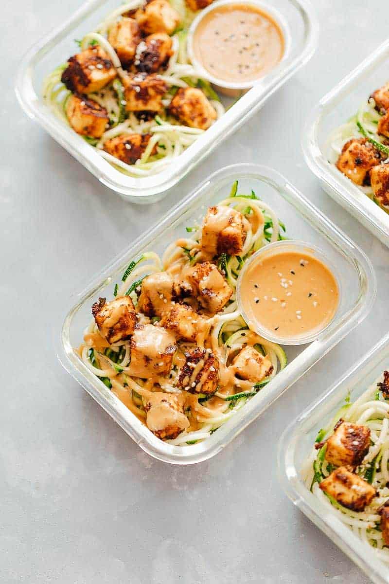 Crispy Sesame Tofu Zucchini Noodles in meal prep containers with peanut sauce