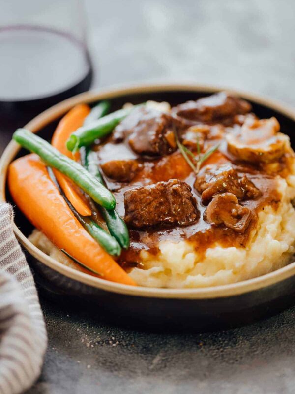 Pressure Cooker Beef Bourguignon served with mashed potatoes and grilled veggies in a black plate.