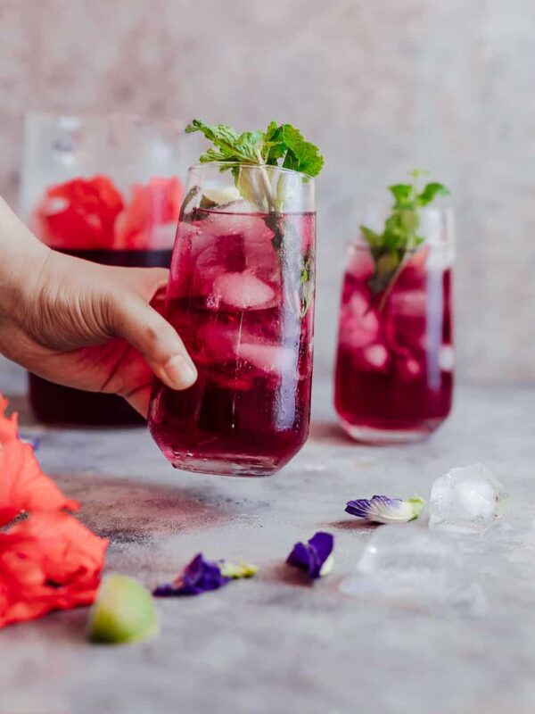 Hibiscus iced tea finished off with mint, lemon and served in glasses.