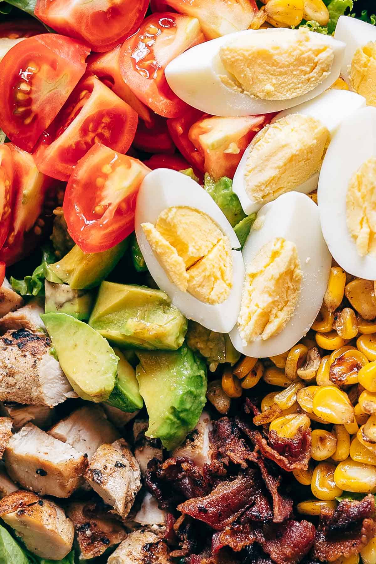 Chicken Cobb Salad served in a bowl - it has lettuce, tomatoes, chicken, bacon, corn and boiled eggs