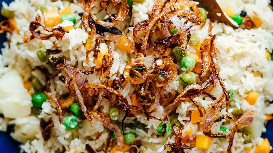 Pressure cooker veg pulao served in a bowl with crispy onions on top