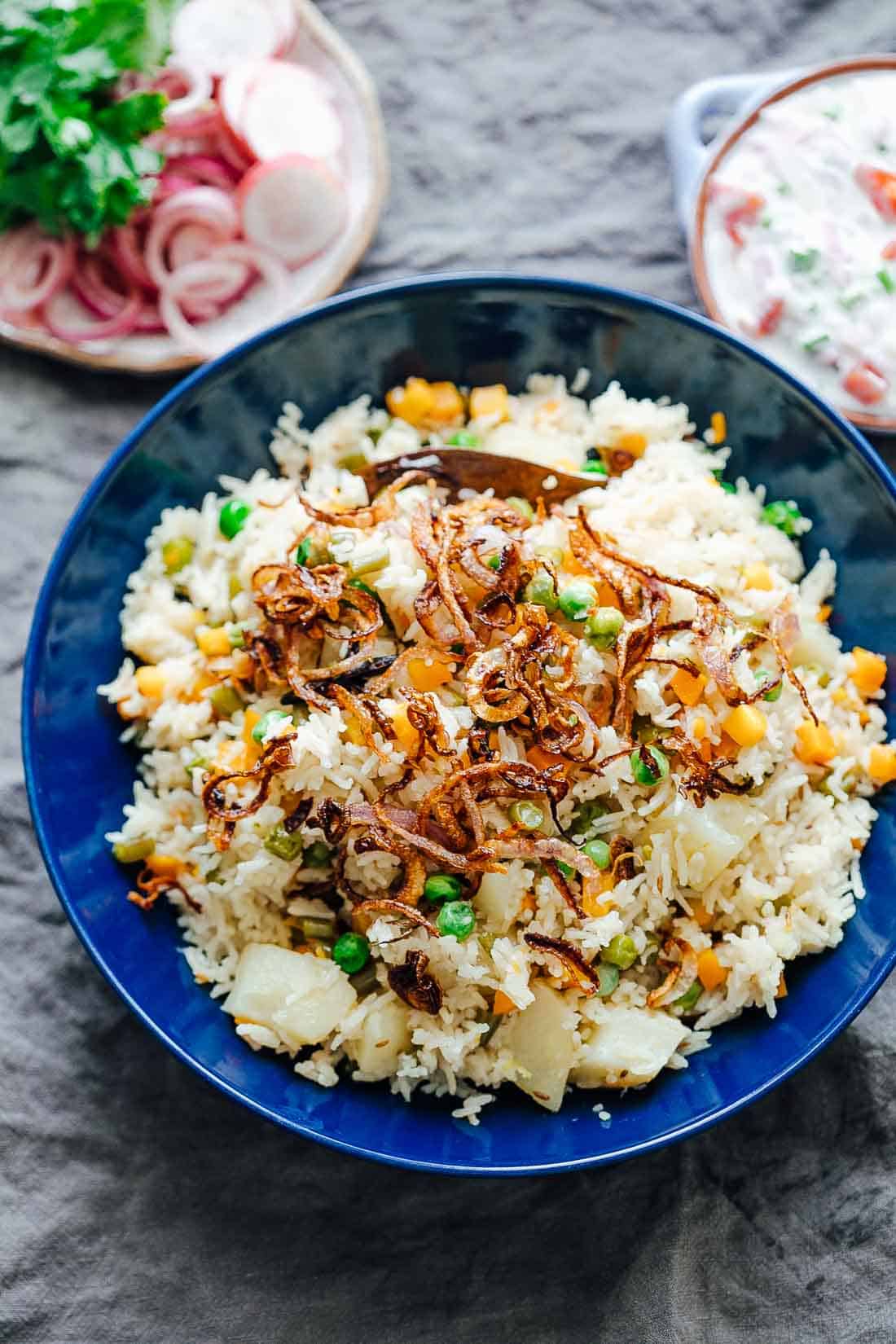Pressure cooker veg pulao served in a bowl with crispy onions on top