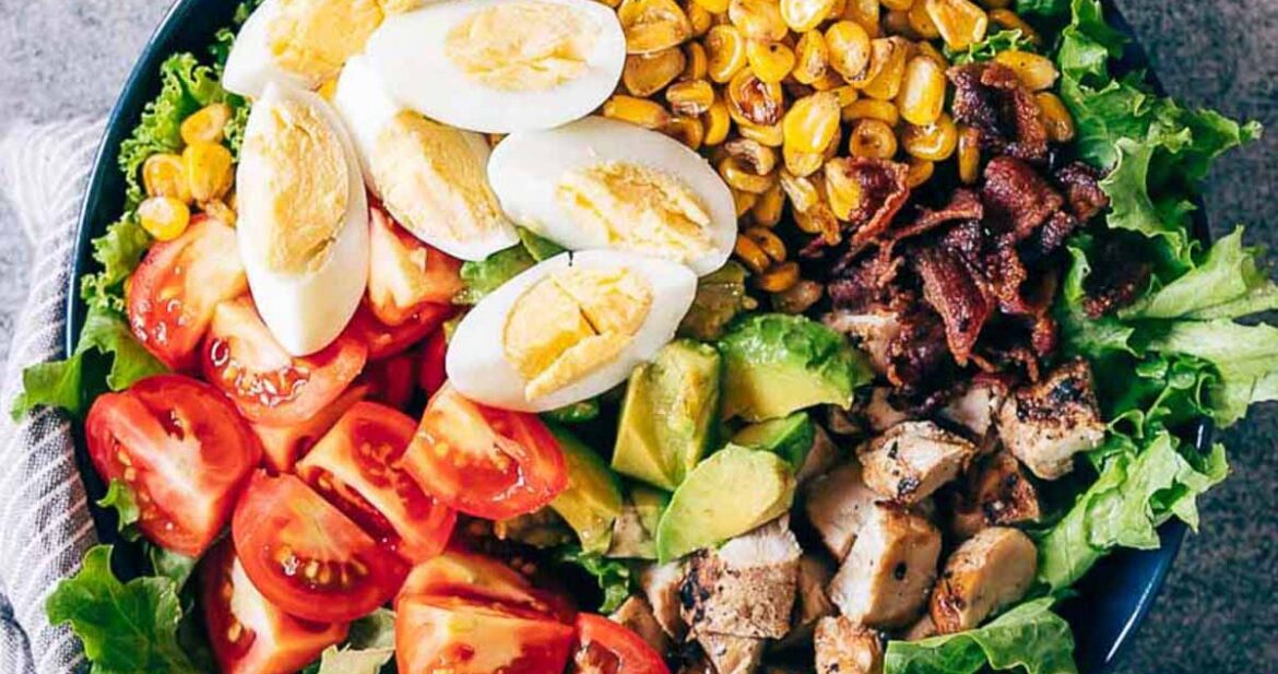 Chicken Cobb Salad served in a bowl - it has lettuce, tomatoes, chicken, bacon, corn and boiled eggs