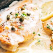Closeup of creamy lemon chicken scallopini with lemon slices and capers on top