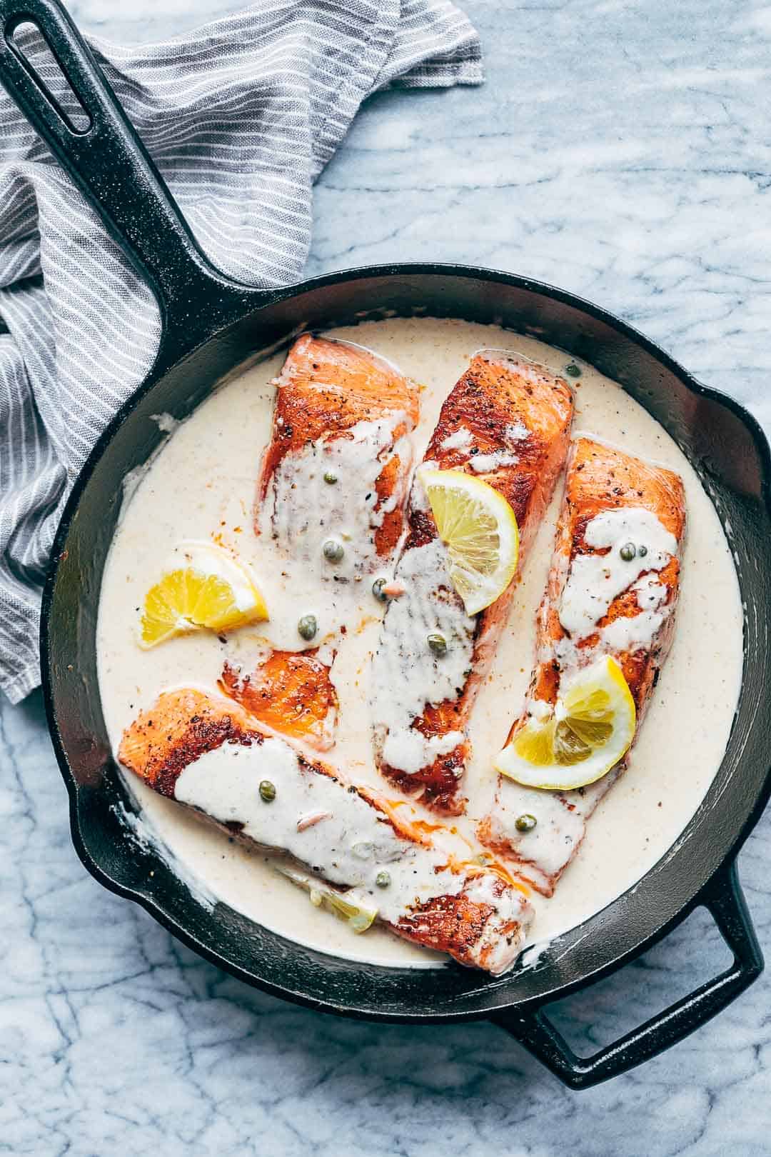 Creamy salmon piccata nestled in a lemon sauce straight off the flame in a cast iron pan