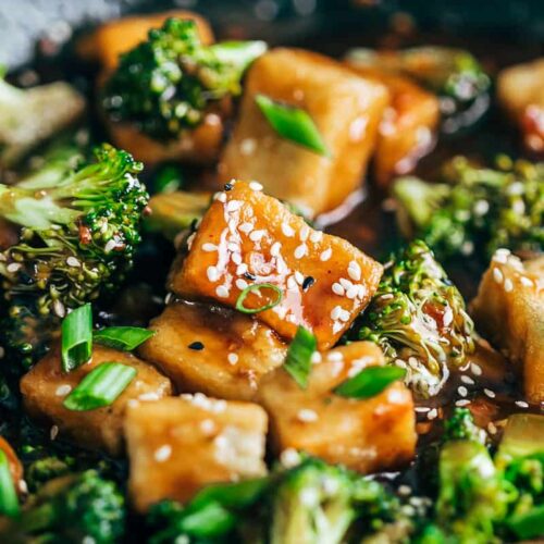 Closeup of crispy tofu broccoli stir fry garnished with toasted sesame seeds and spring onions.