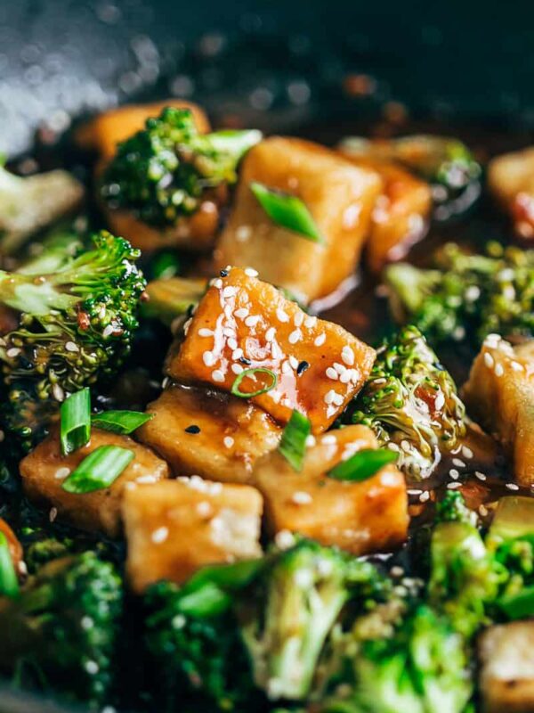 Closeup of crispy tofu broccoli stir fry garnished with toasted sesame seeds and spring onions.