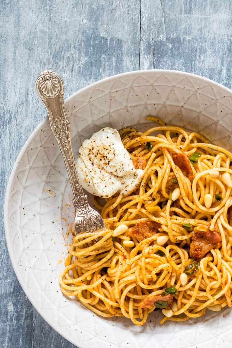 Closeup of bacon garlic harissa pasta in a white bowl