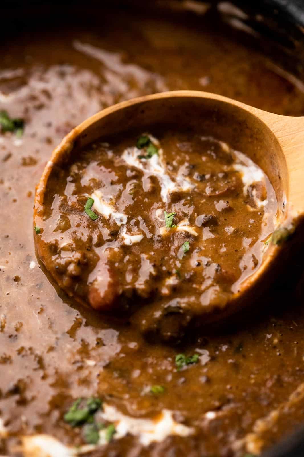 Closeup of a ladleful of dal makhani to show the creamy texture of the lentils