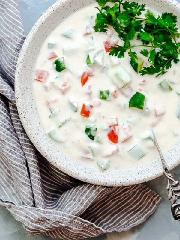 Indian raita served in a white bowl topped with coriander or cilantro