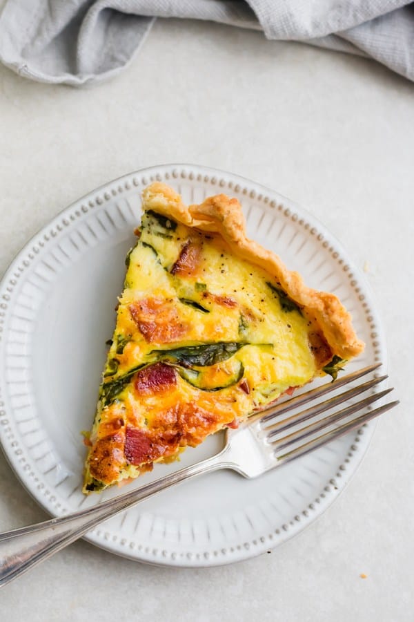 A slice of breakfast quiche on a white plate - one of the bacon recipes