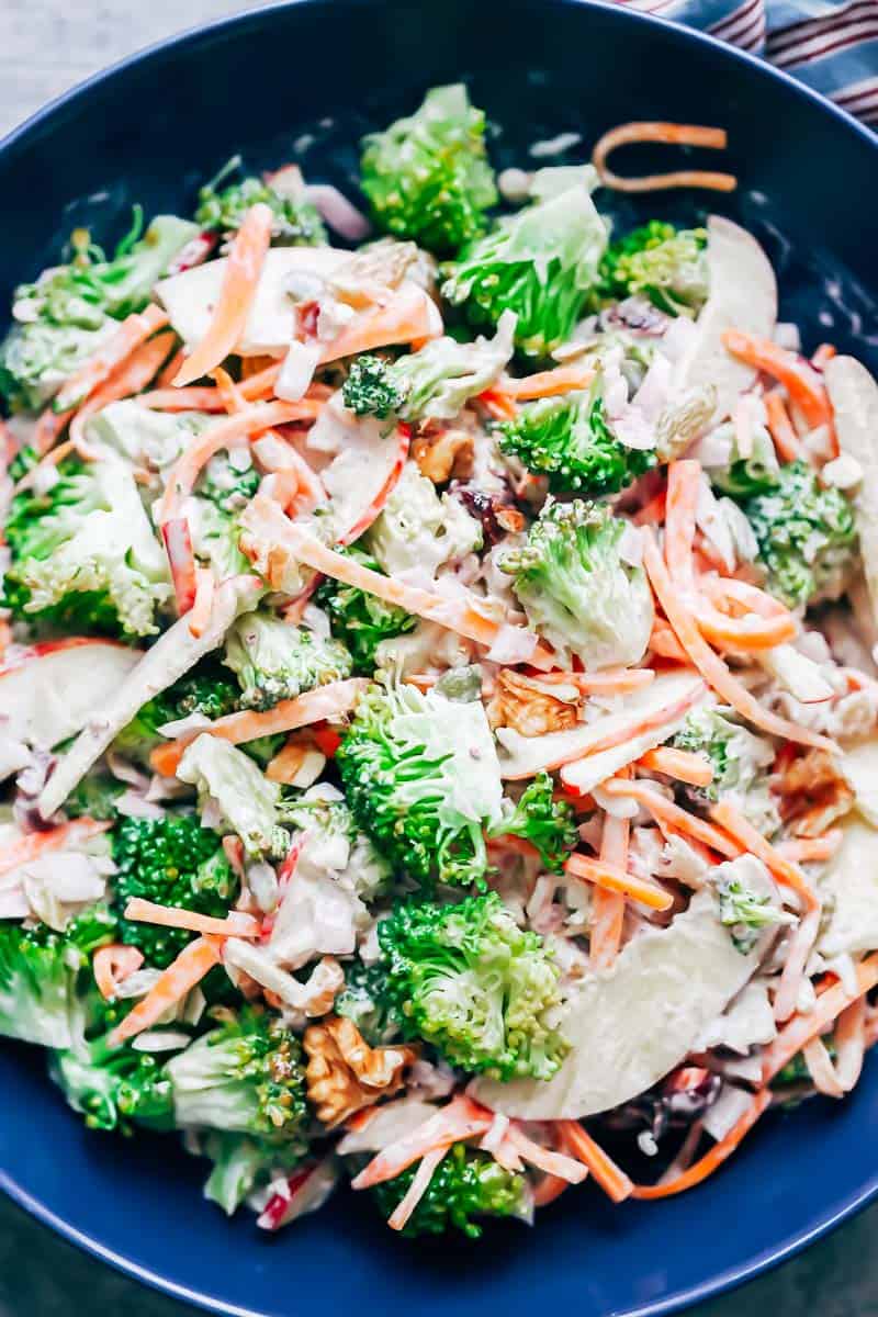 Closeup of apple broccoli walnut salad to showcase the bright green broccoli, red apples and bright carrots in the salad