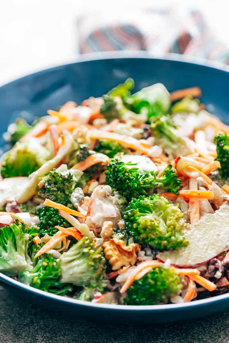 Close up of creamy apple broccoli walnut salad tossed in a creamy dressing, and served in a blue bowl