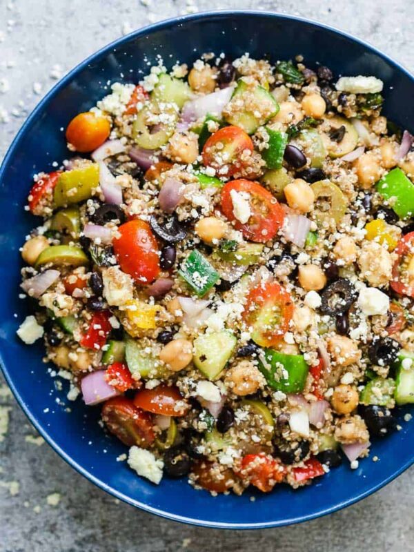 Mediterranean quinoa salad served in a blue bowl sprinkled with crumbled feta.