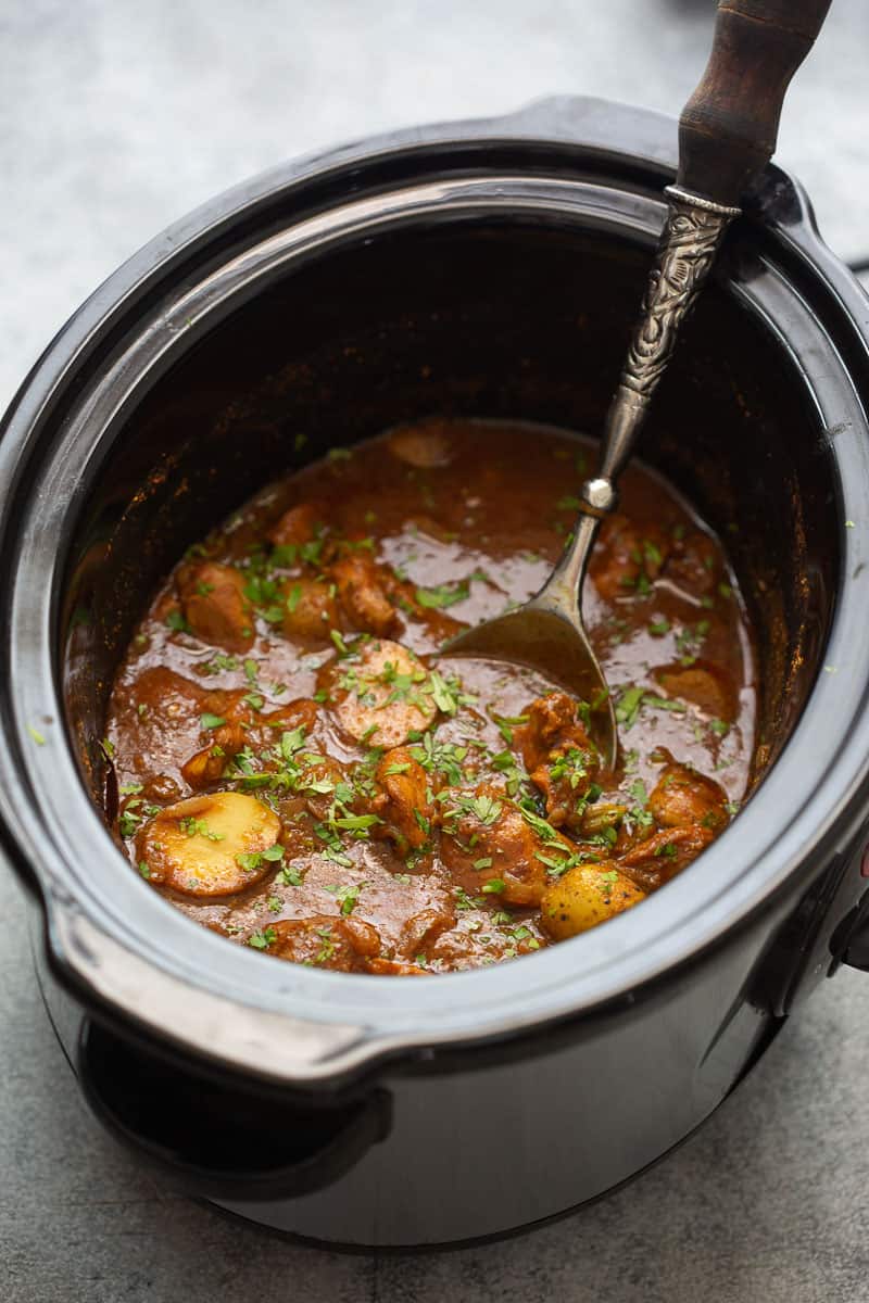 Slow cooker chicken curry served in a slow cooker with chopped coriander sprinkled on top
