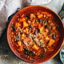 Winter Vegetarian Minestrone Soup served in a bowl topped with parmesan and olive oil