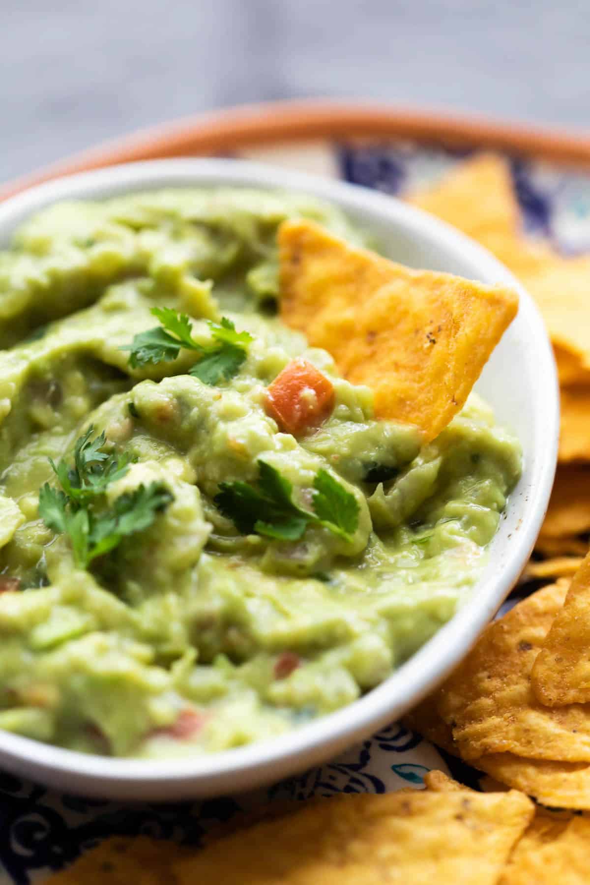 Close up of homemade guacamole with a chip in the bowl.