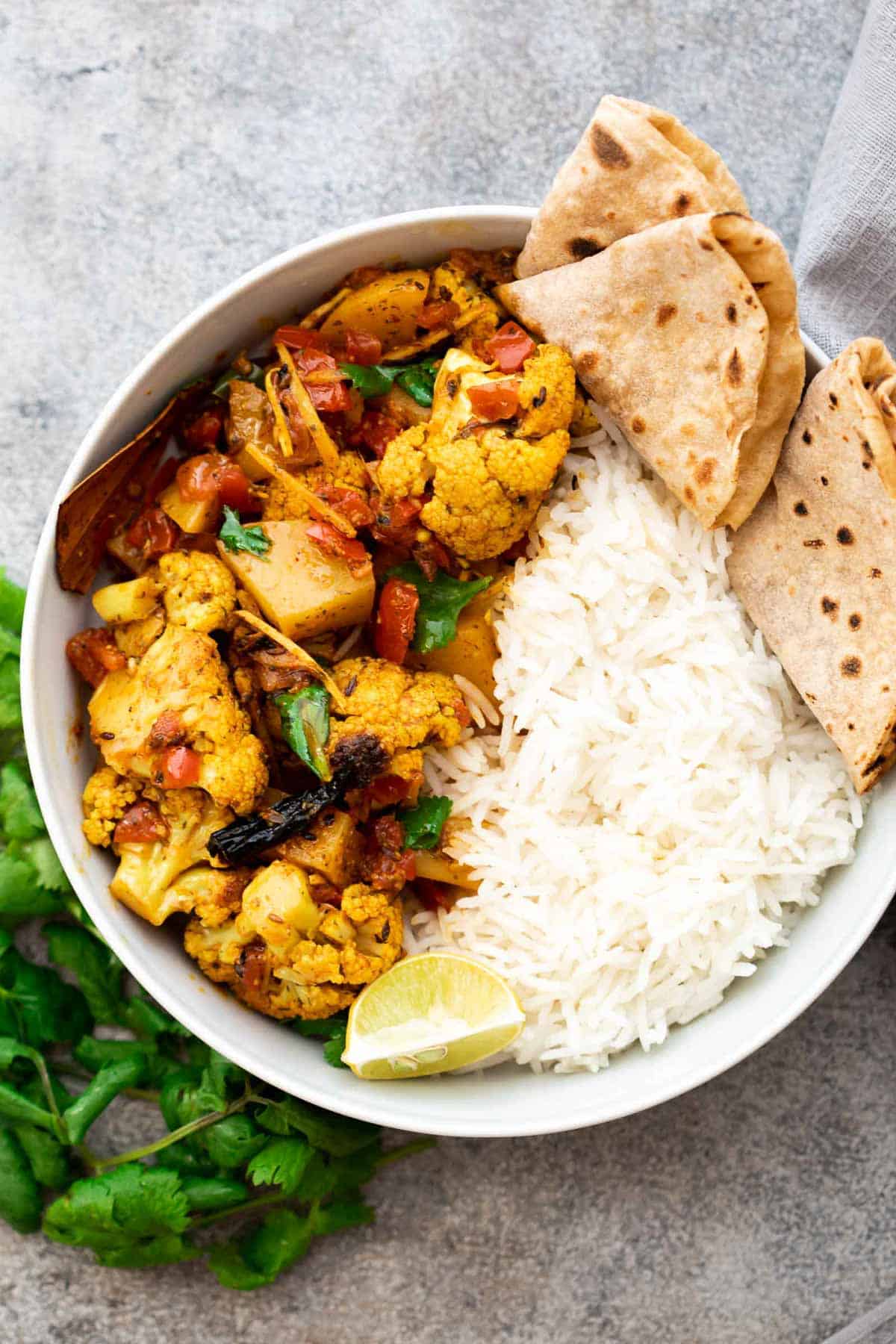Aloo Gobi Masala served in a bowl with steamed rice and chapatis