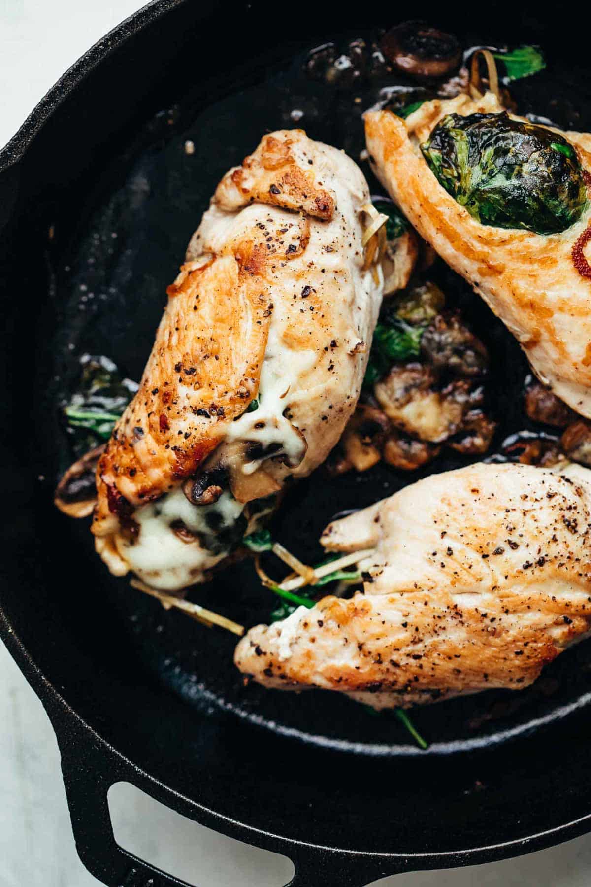 Spinach Mushroom stuffed Chicken Breast cooked in a cast iron pan.
