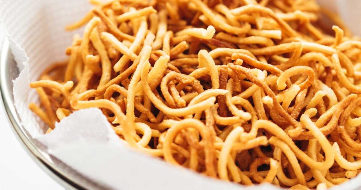 Fried noodles draining on paper towels in a colander to get rid of any excess oil