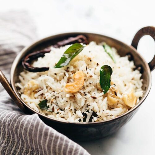 Coconut rice served in a kadhai topped with roasted cashews and curry leaves