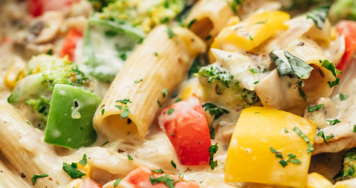 White sauce pasta with vegetables directly from the stovetop in a pan.