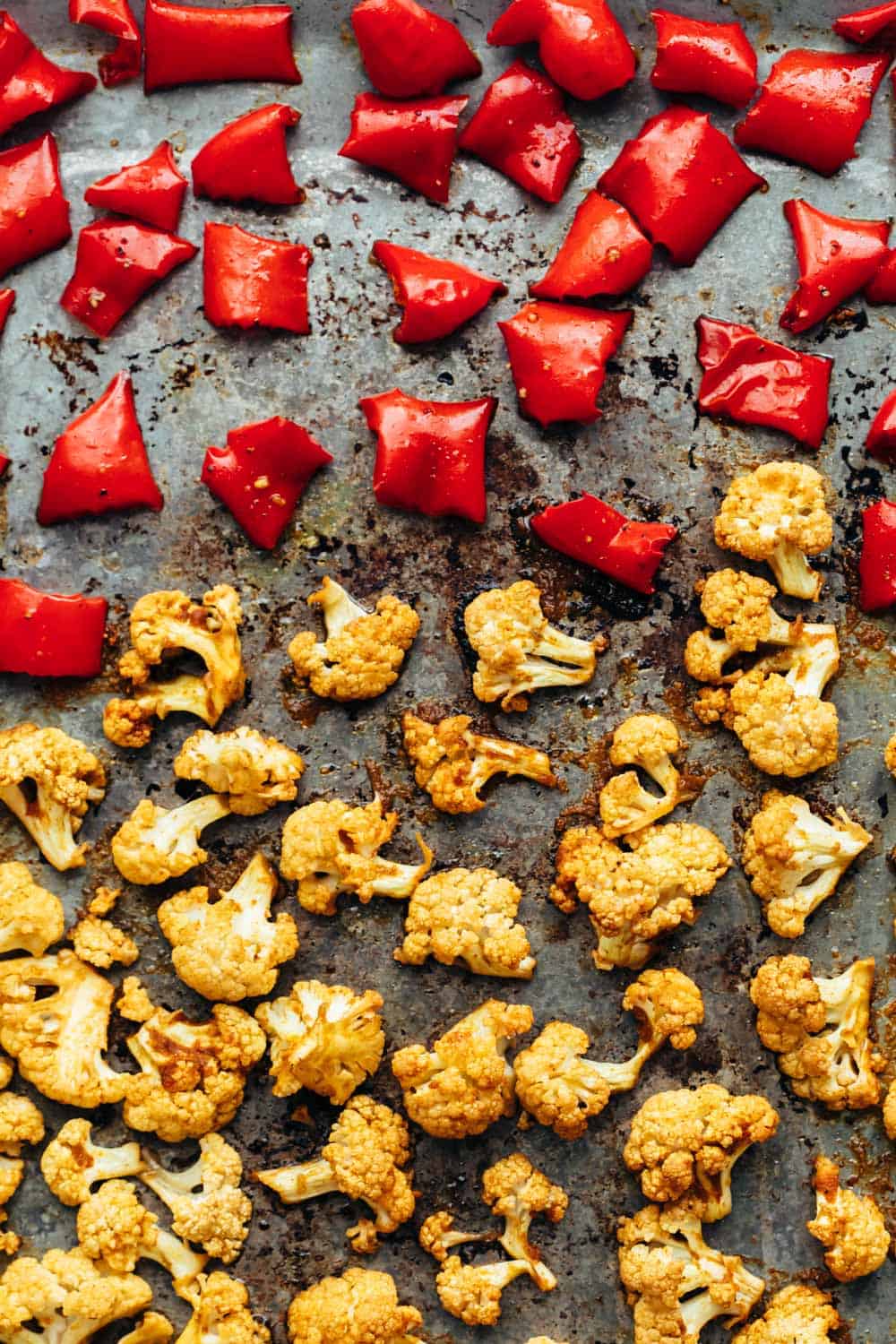 Oven roasted cauliflower and bell peppers on a baking sheet for curried roasted cauliflower bowl
