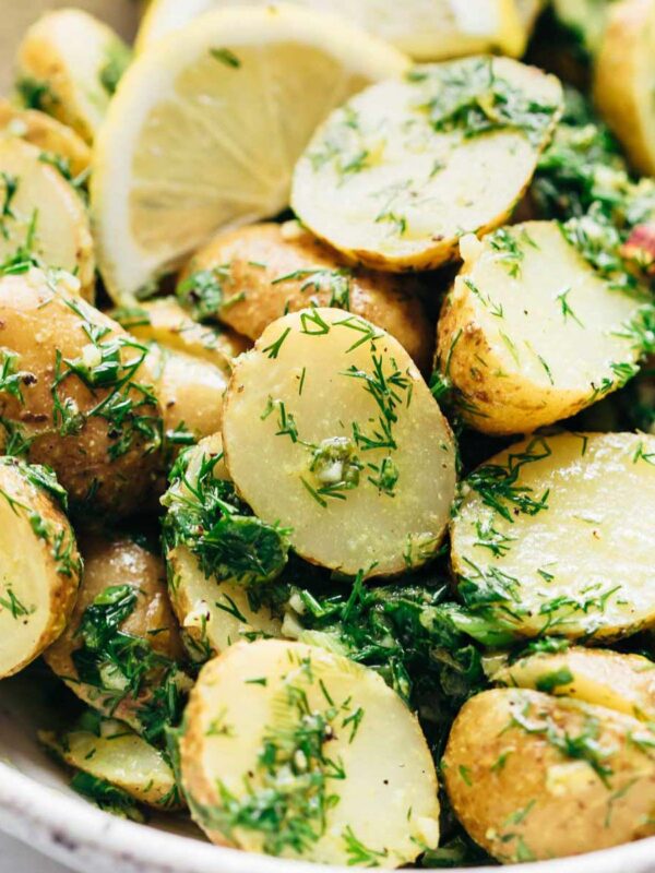 Close up of Healthy Lemon Dill Potato Salad (no mayo) served in a white speckled bowl with lemon wedges