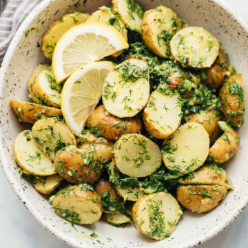 Healthy Lemon Dill Potato Salad (no mayo) served in a white speckled bowl with lemon wedges
