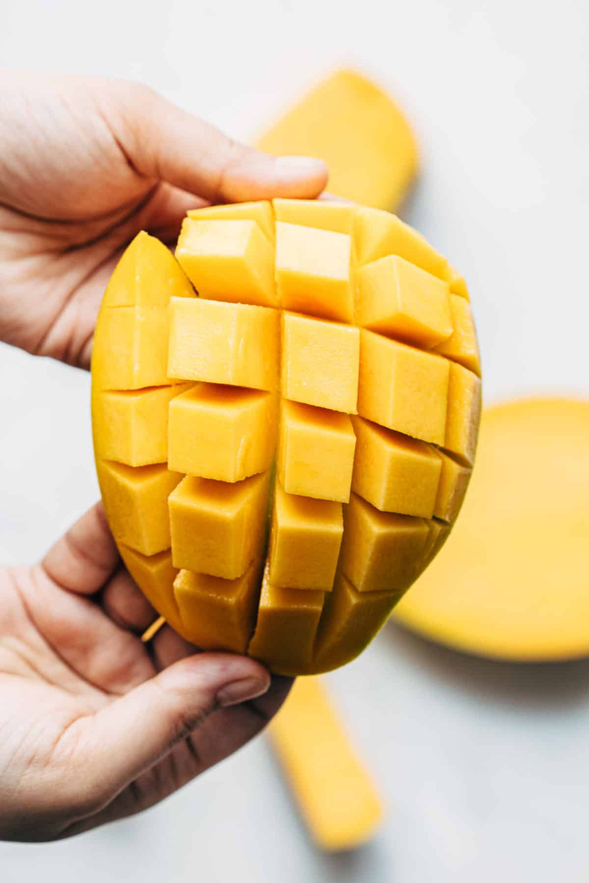 A peeled mango cut into dices by making horizontal and vertical cuts.
