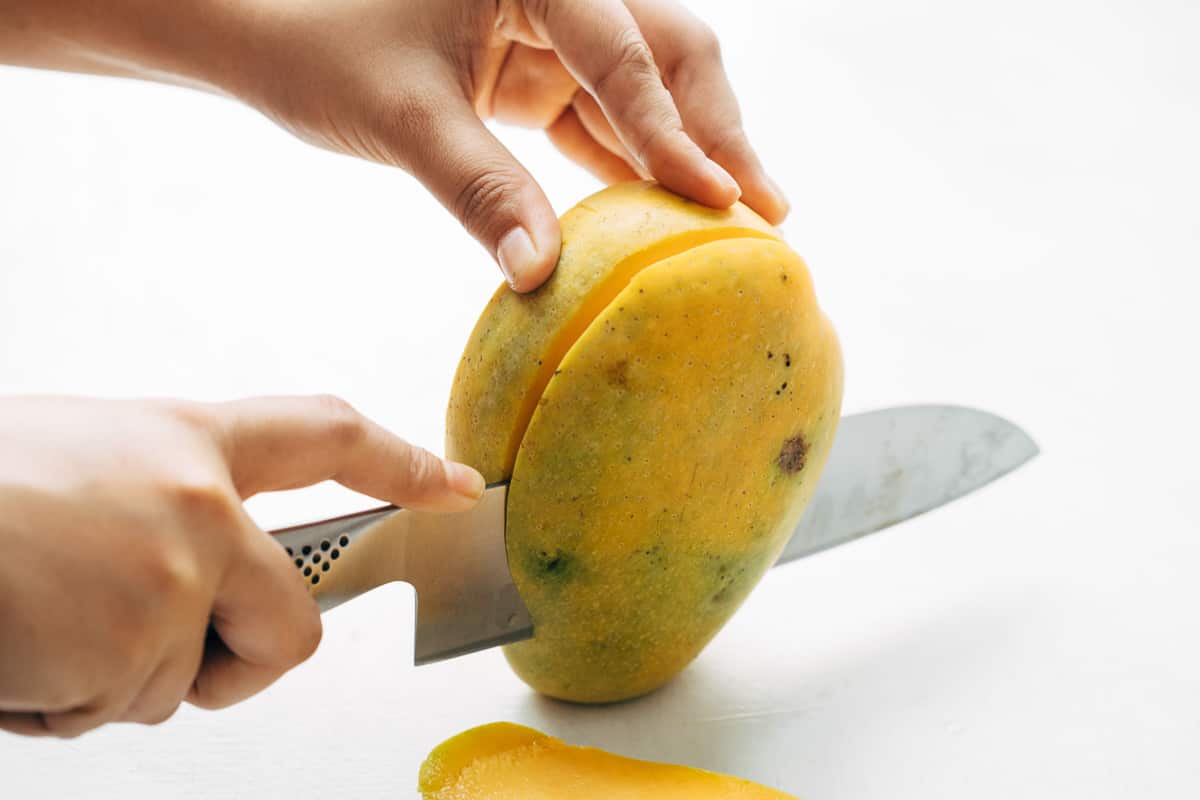Cheeks of a mango being cut out.