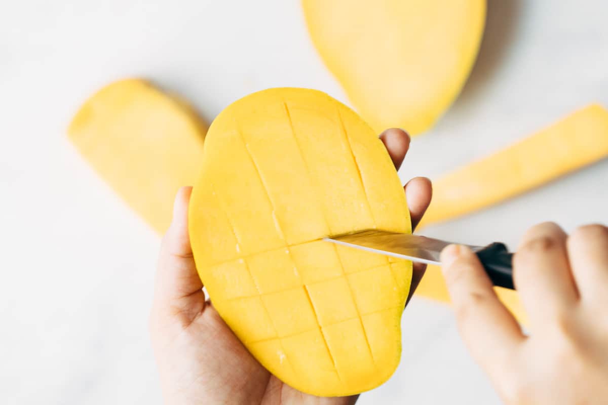 Horizontal cuts being made on a mango to cut it into dices.