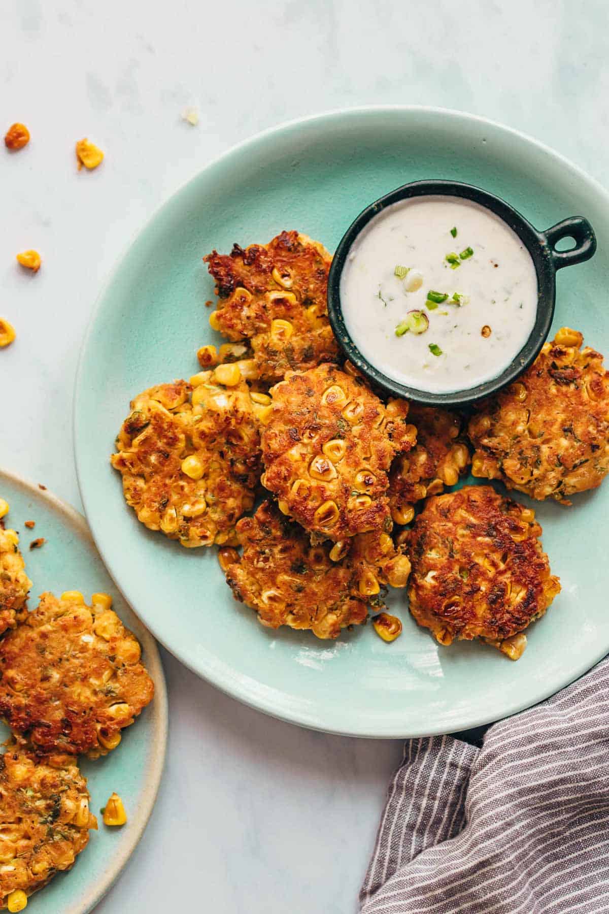 Mexican corn fritters served on a blue plate with a creamy dip on the side