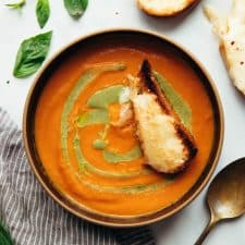 Roasted tomato pesto soup served in a bowl with toasted cheesy bread