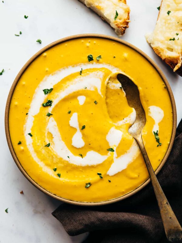 Creamy roasted pumpkin soup in a bowl with cheesy bread