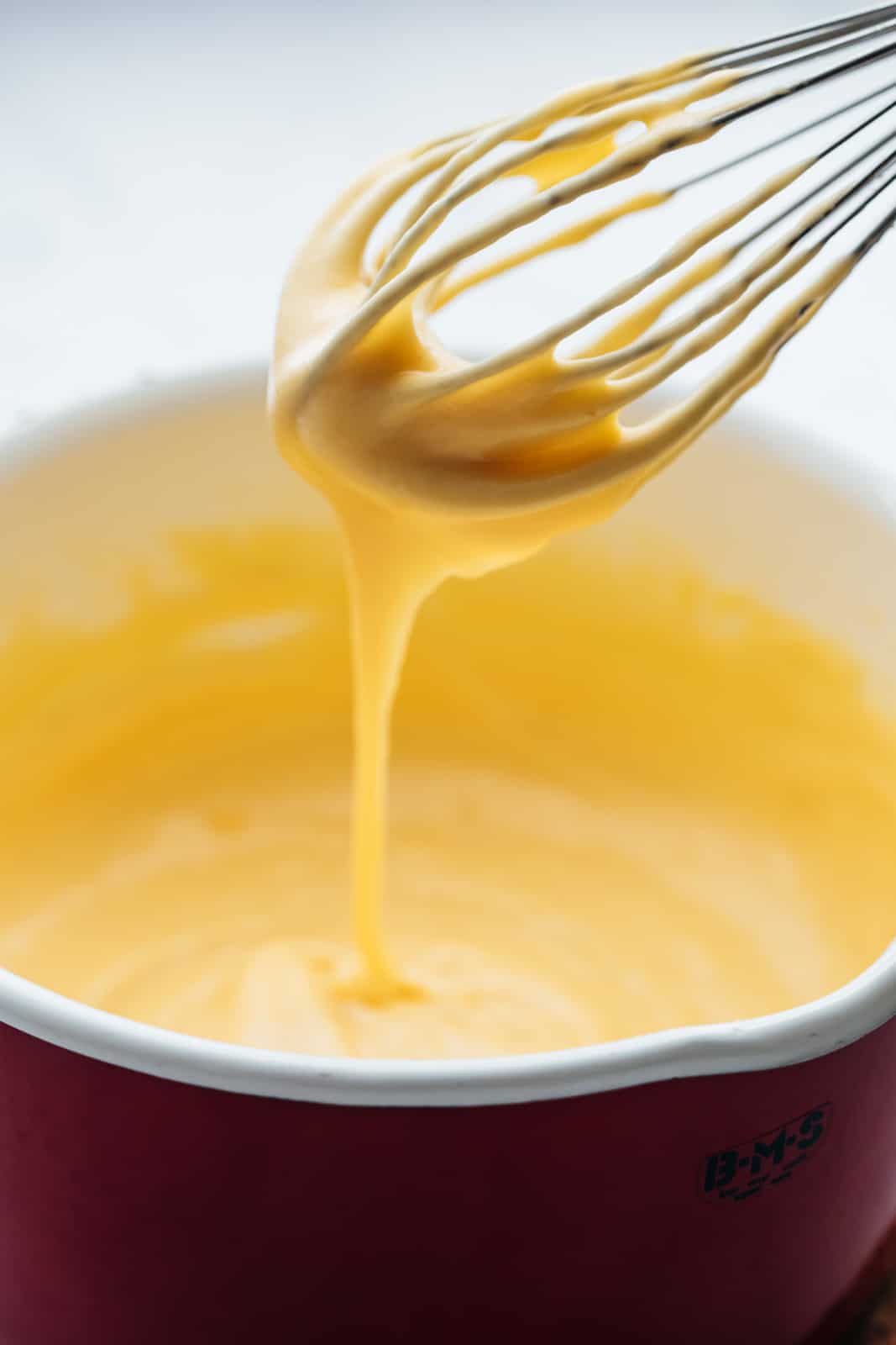 Spicy nacho cheese sauce consistency being shown with a whisk