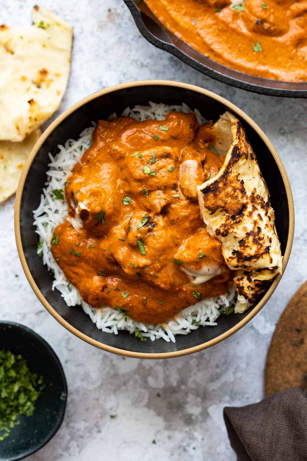 Butter Chicken served in a bowl with rice and naan bread