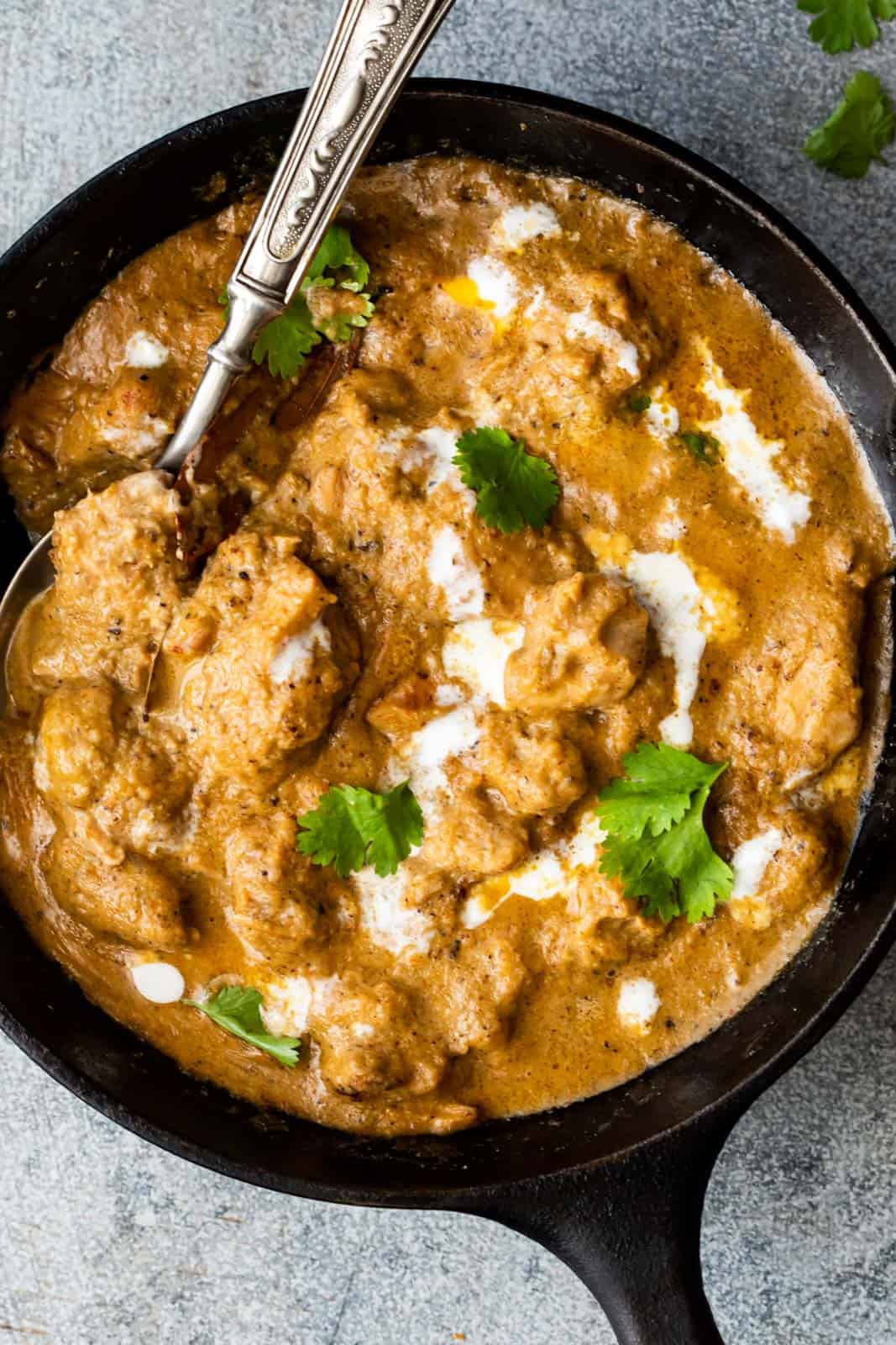 Easy Chicken Korma garnished with cream and served in a pan