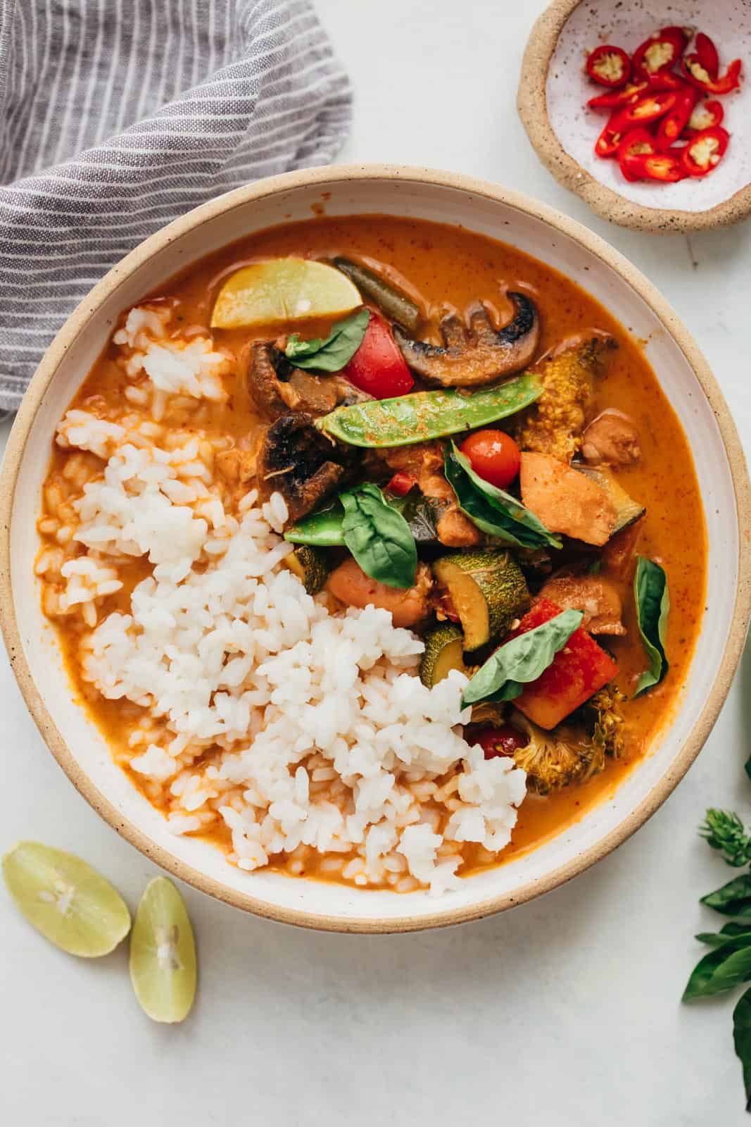 Instant pot Thai chicken curry served in a bowl with rice, thai red chillies and lemon wedges