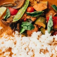 Closeup of Instant pot Thai chicken curry served in a bowl with rice, thai red chillies and lemon wedges