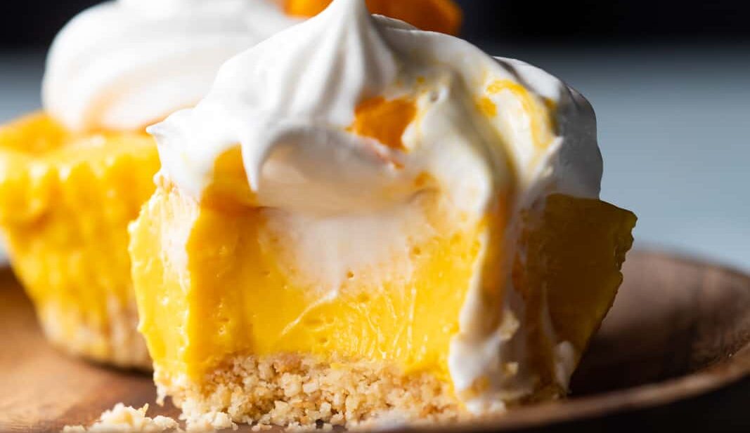 Closeup of a bite takes out of mini mango cheesecakes to show texture