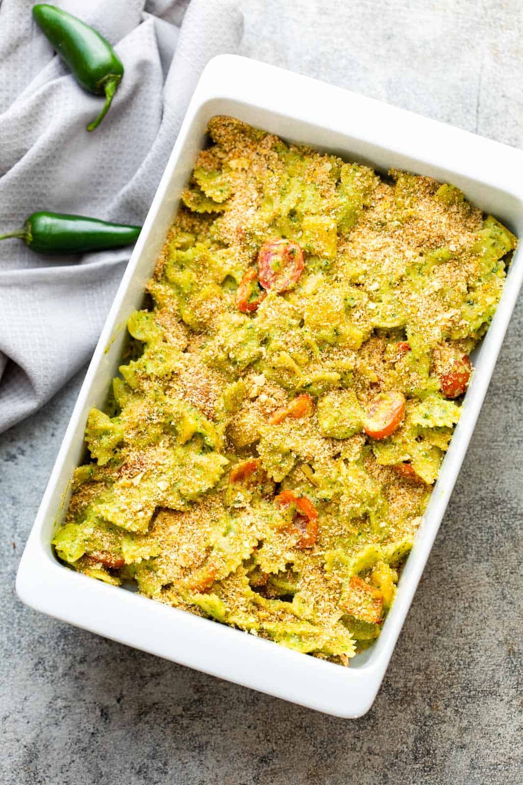 Baked pasta in jalapeno pesto in a white casserole dish straight from the oven
