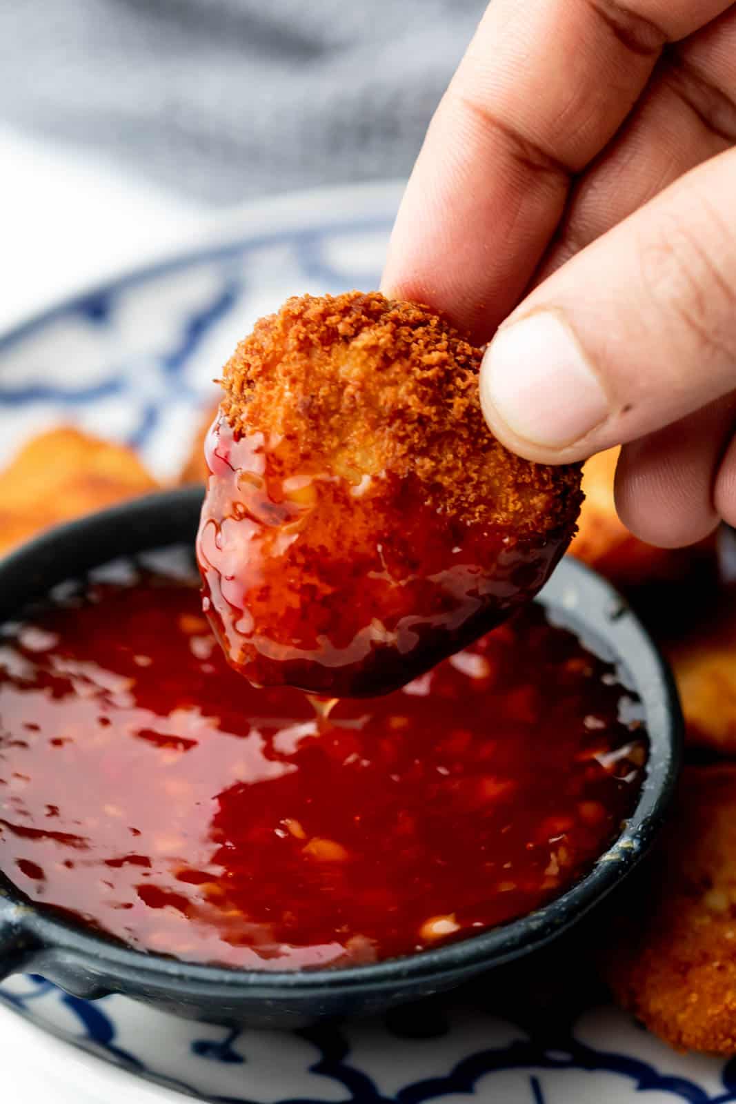 Chicken nugget being dipped into thai sweet chili sauce