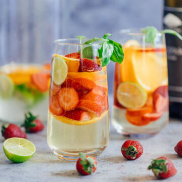 Strawberry Orange White Wine Sangria served in two glasses with limes and basil