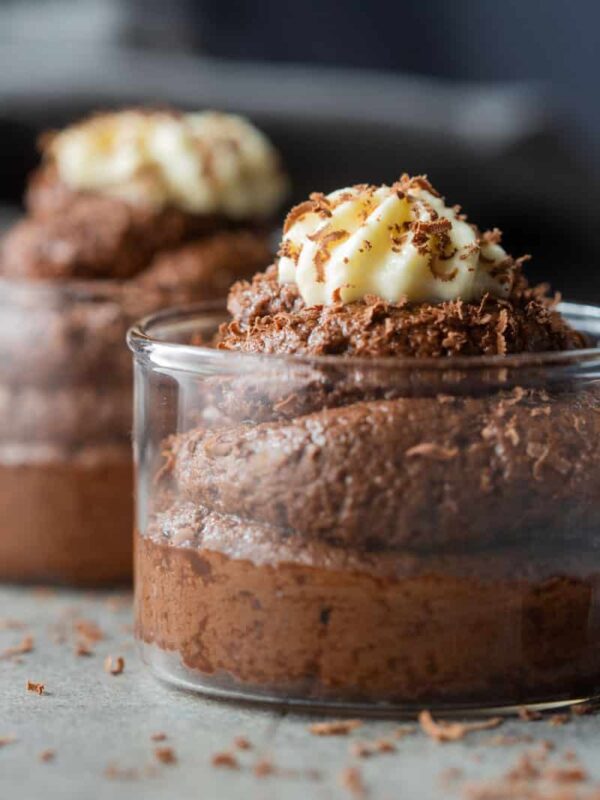 eggless chocolate mousse served in glass jars topped with whipped cream and a sprinkle of grated chocolate